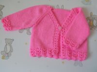 babies handknitted cardigan in fuschia with lacey edging to cuffs and welt