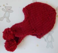 child's handknitted red chunky hat with pompoms